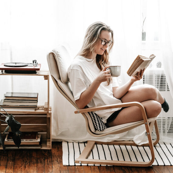Woman sitting in her apartment reading with a cup of tea