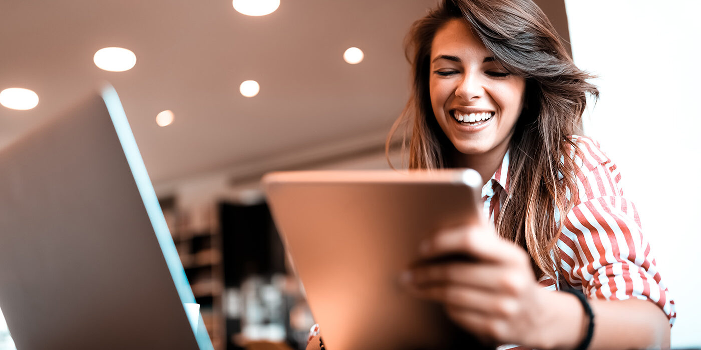 Woman smiling and working while holding her tablet
