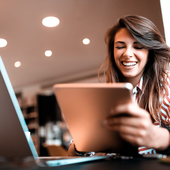 Woman smiling and working while holding her tablet