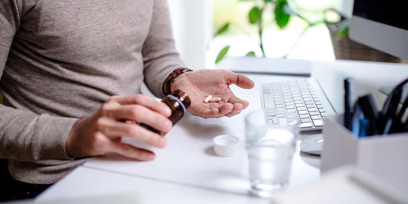 Person at their work desk takes medication