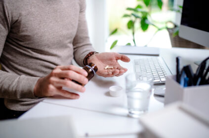 Person at their work desk takes medication